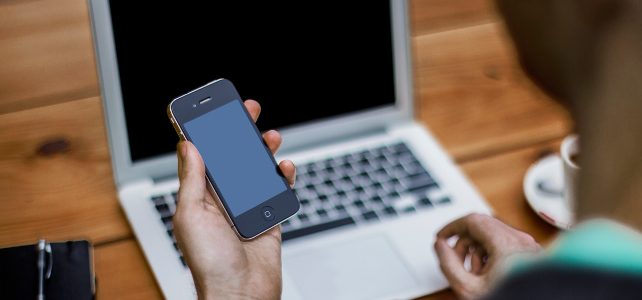 Kontakt mężczyzna przy laptopie trzymający telefon w dłoni